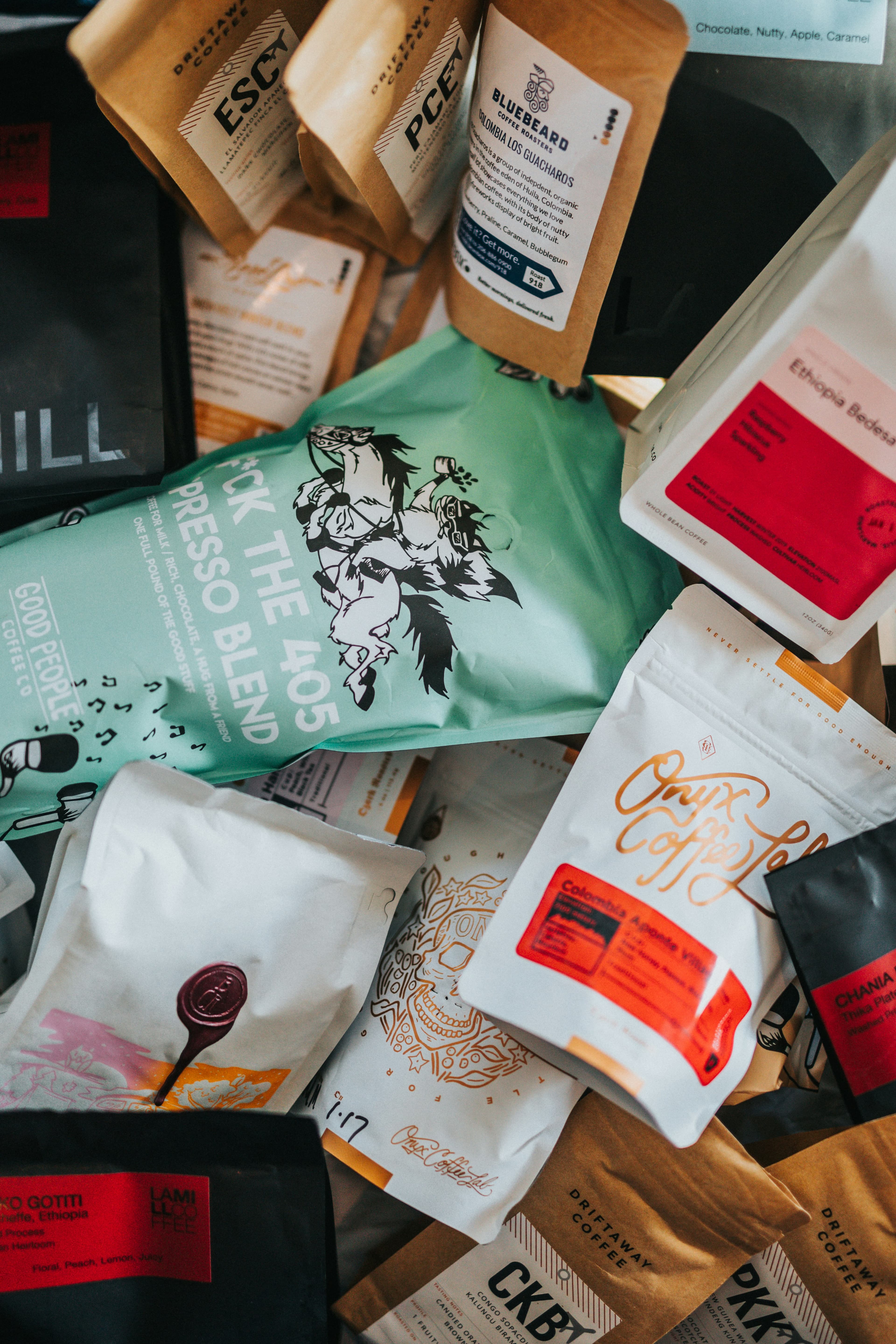 A pile of colorful specialty coffee bags from independent roasters