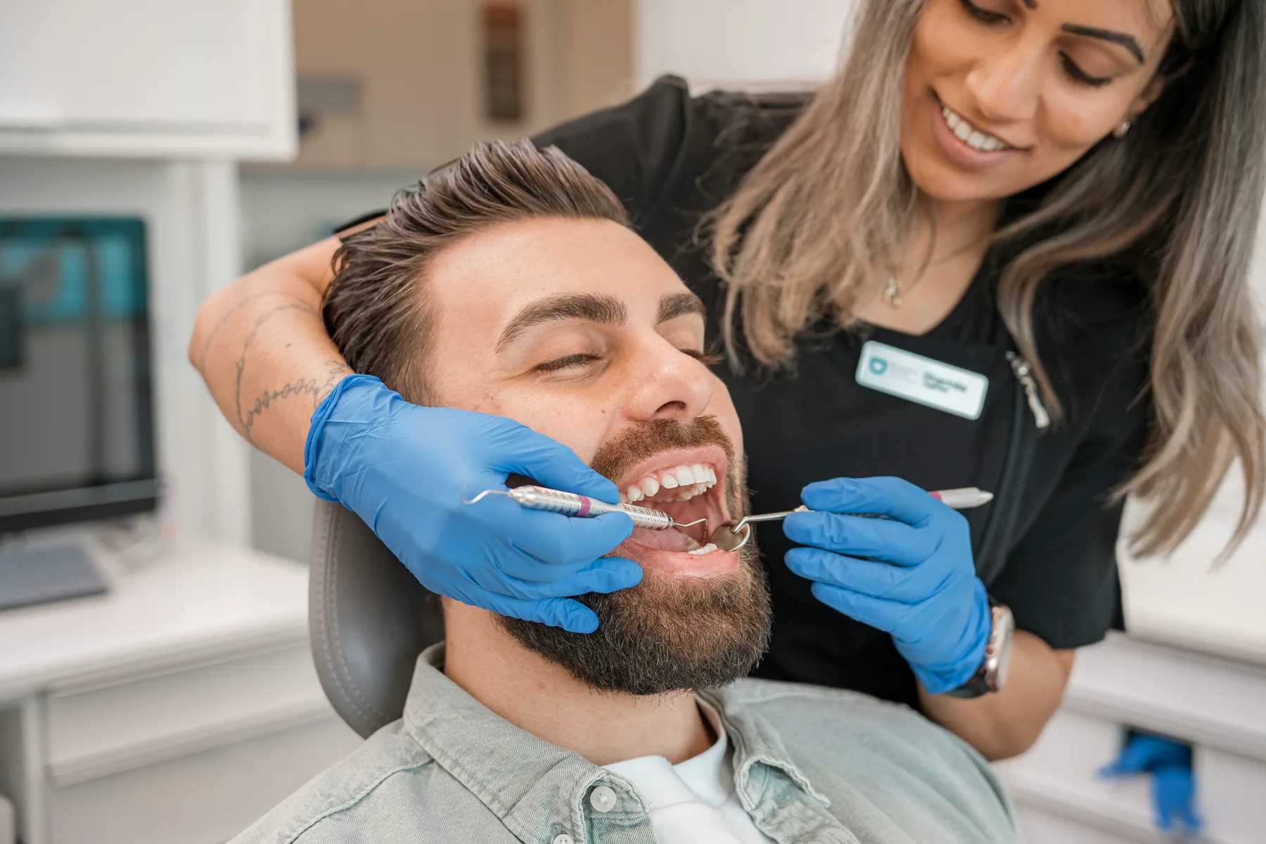 Clinician examining a smiling patient in a modern treatment room
