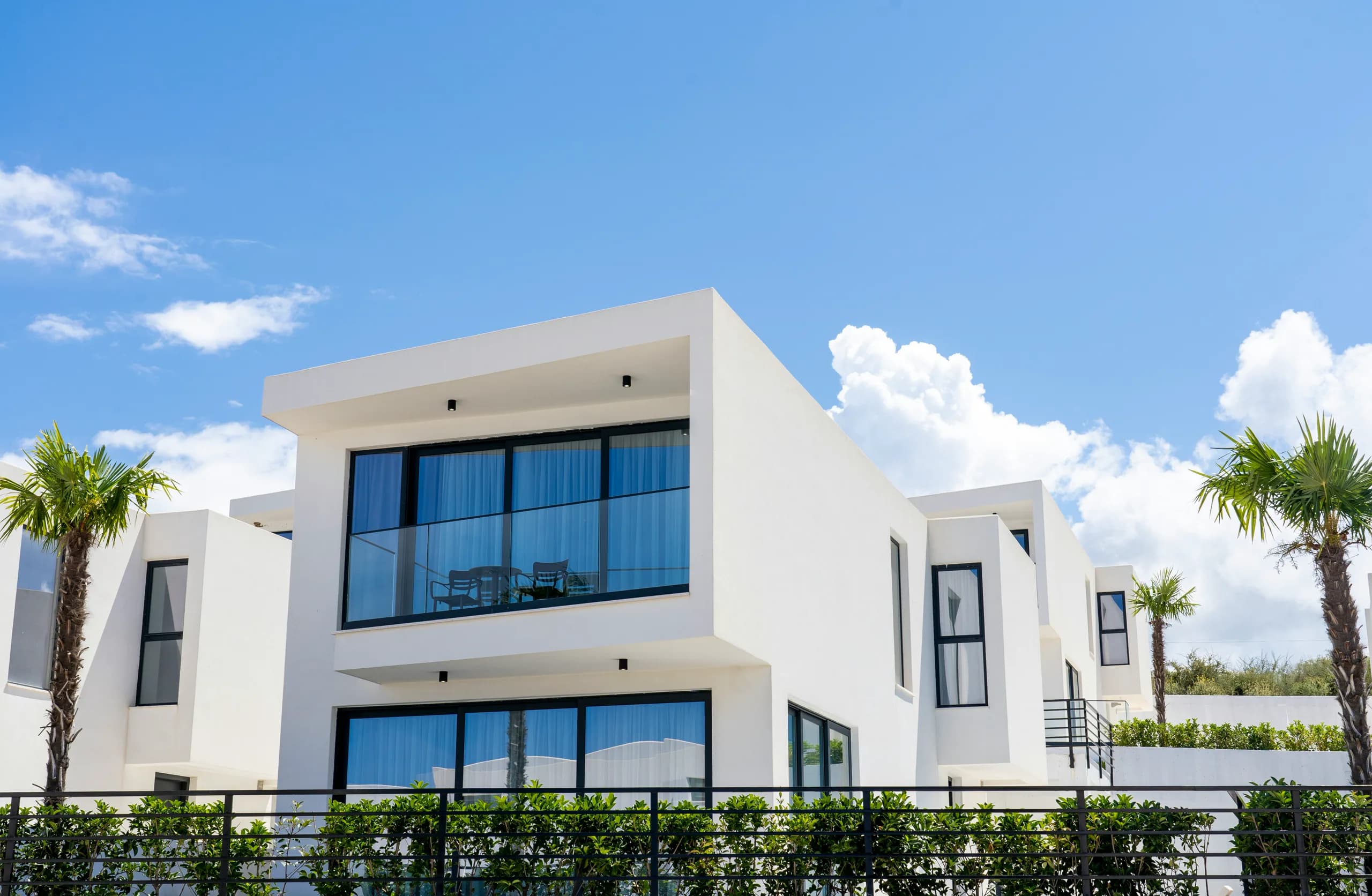 Row of white cube residences between palm trees