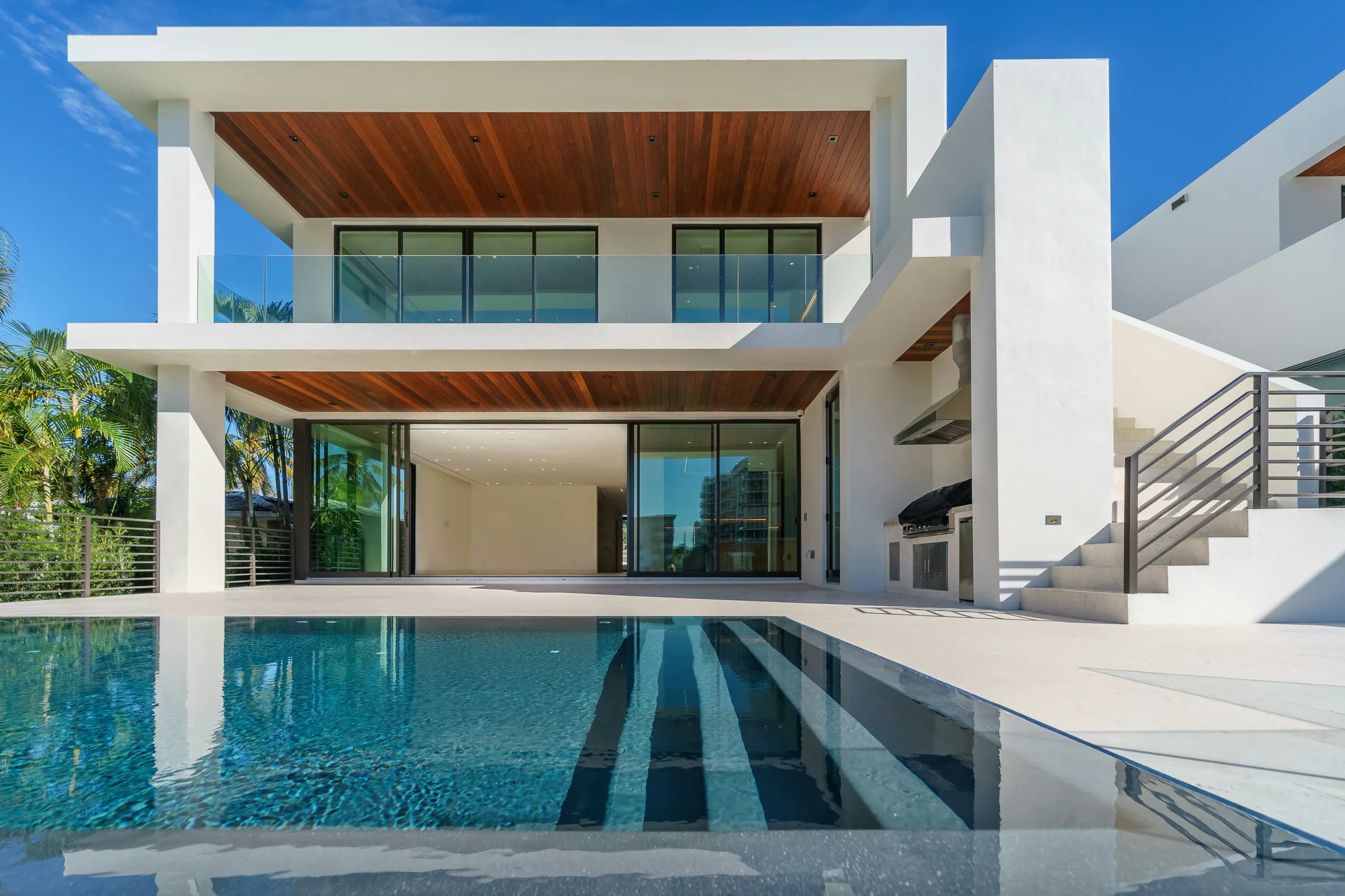 White villa with warm timber ceilings above an infinity pool