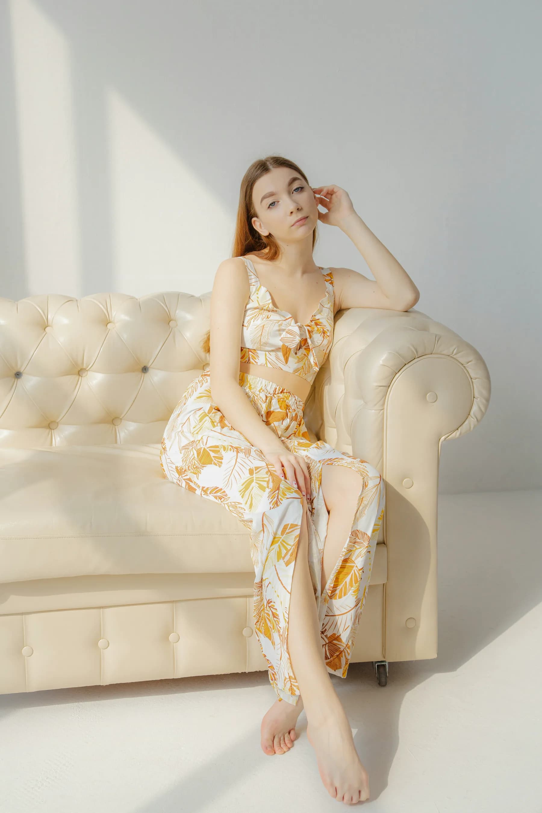 Model in a tropical-print matching set on a cream leather sofa