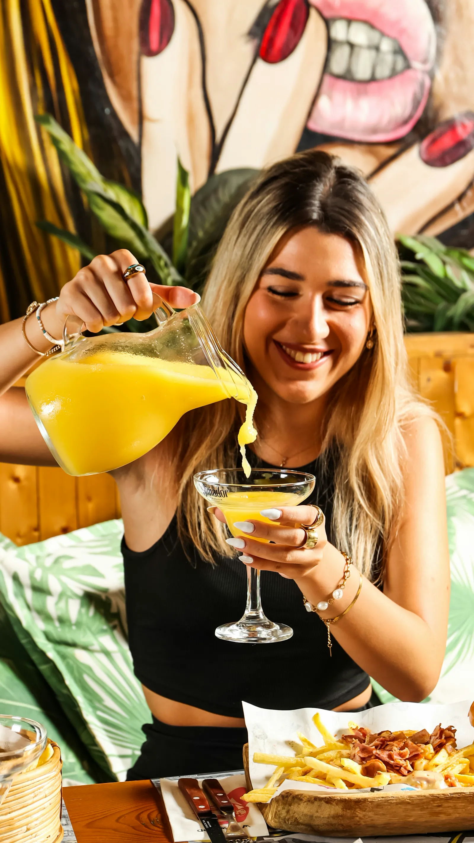 Guest pouring a frozen margarita at a lively table