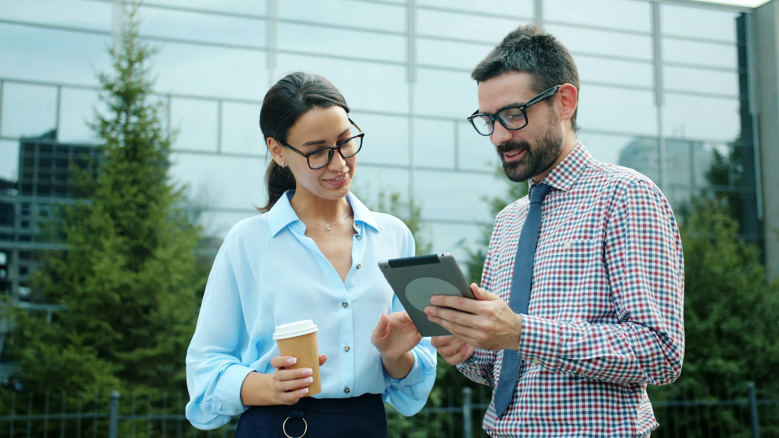 Two agents reviewing a listing on a tablet outside a glass office