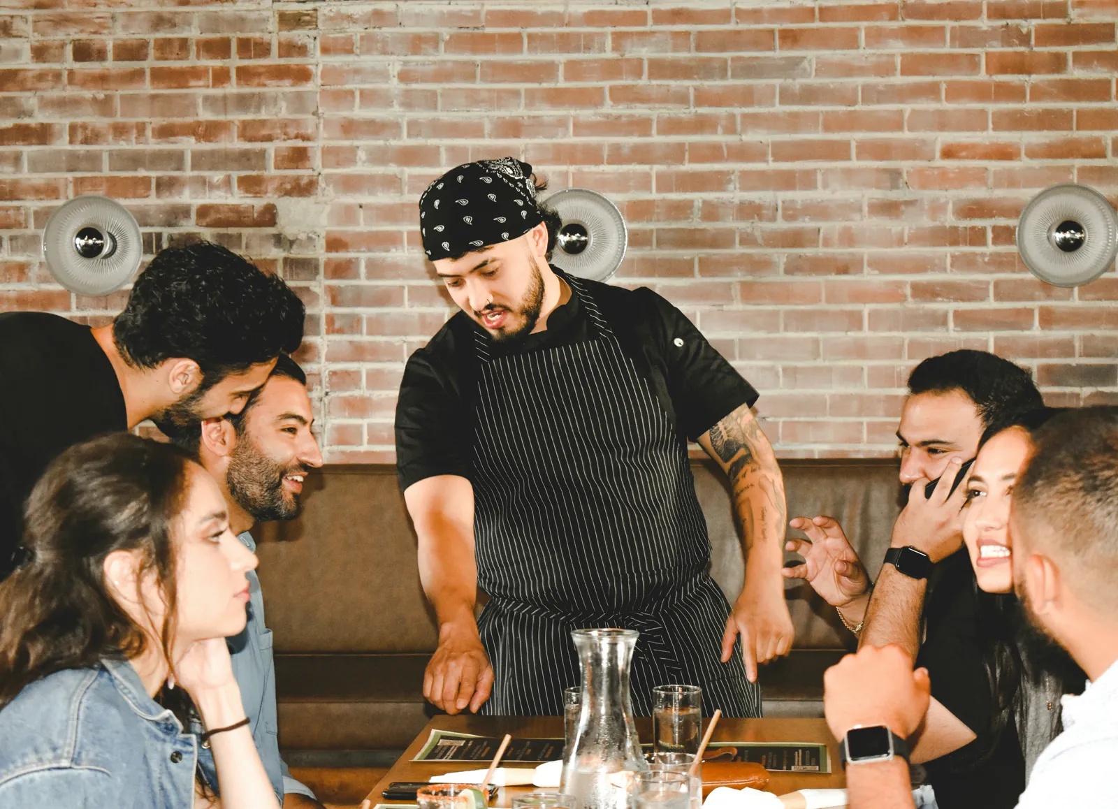 Chef presenting dishes to a full table