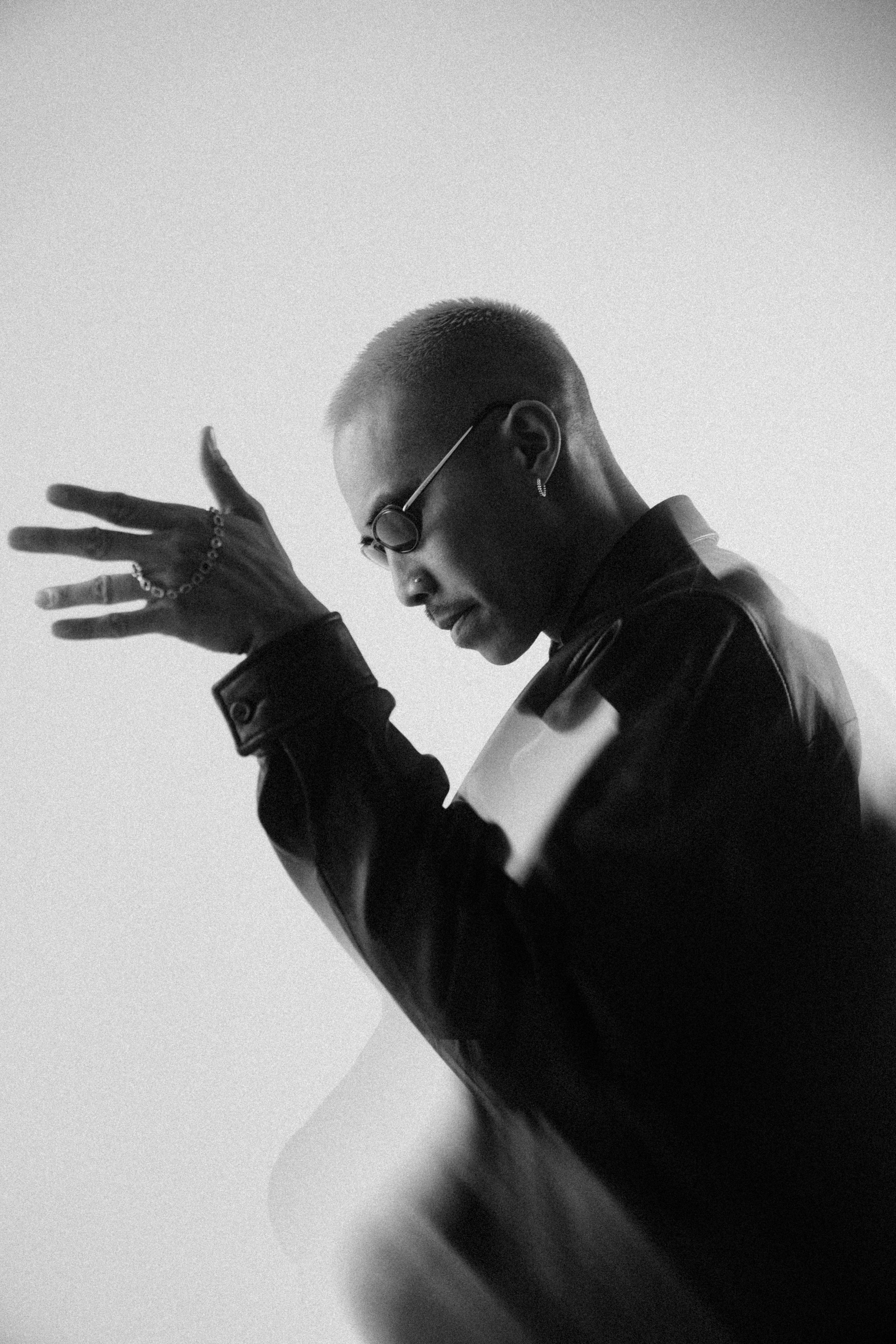 High-contrast black-and-white portrait of a model adjusting a jacket cuff
